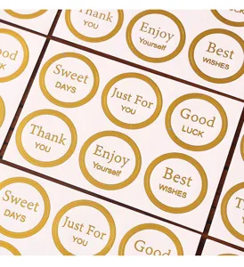 Close-up detail of gold foil round sealing stickers with elegant greetings for gifts.