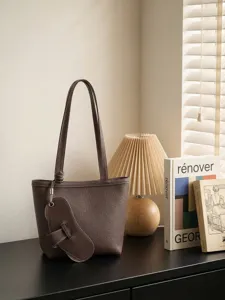Brown leather tote shoulder bag with long handles and unique charm for women daily commute.