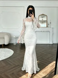 Precioso vestido largo de sirena en encaje blanco con manga larga y corte ajustado.