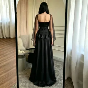 Détail de la robe de soirée noire avec design sans bretelles, manches transparentes et basque.