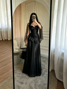 Élégante robe de soirée noire sans bretelles avec manches cape transparentes et volants.