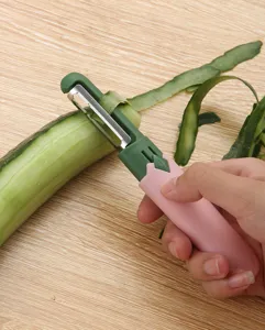 Handheld 2-in-1 fruit peeler detail showing dual stainless steel blades in kitchen use.