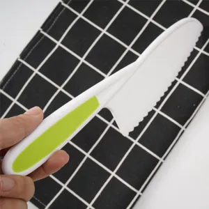 Close-up detail of plastic child safety bread knife serrated blade with green handle.