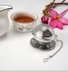 Stainless steel tea infuser detail shot with chain and mesh ball filter on clean surface.