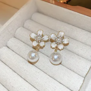 Close-up detail of elegant cherry blossom flower and hanging pearl earrings on soft tray