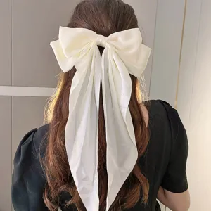 Vista detallada de un gran lazo para el pelo de tela blanca crema con cintas largas, elegante.