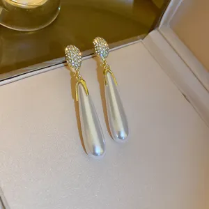 Detailed view of elegant long teardrop pearl rhinestone earrings in gold tone, stunning design.