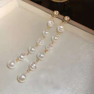 Elegant long dangle earrings featuring irregular baroque pearls and sparkling crystal studs with gold chains.