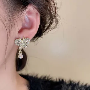 Detail shot of elegant butterfly rhinestone drop earrings, sparkling gold jewelry for women.