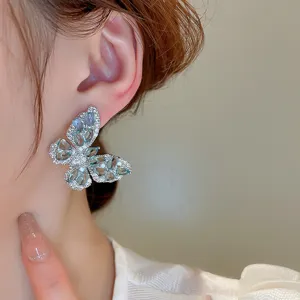 Close-up detail of exquisite zircon butterfly ear studs featuring sparkling blue gemstone details.