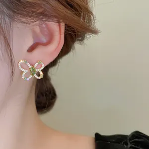Close-up detail of exquisite butterfly ear studs with sparkling zirconia and green center stone.