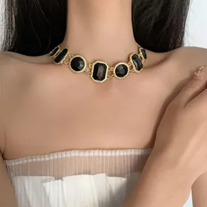 Close-up detail of vintage style gold-tone choker necklace featuring alternating black geometric stones.