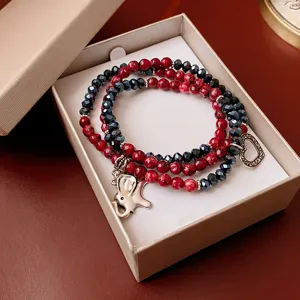 Multi-layer beaded bracelet featuring red and dark beads with elephant and heart charms.
