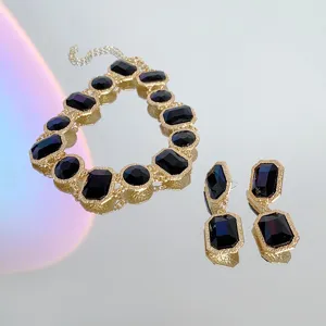 Close-up detail of vintage style gold-toned necklace and earrings set with dark crystals.