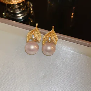 Detailed close-up of French style gold leaf and pearl earrings, elegant jewelry detail view.