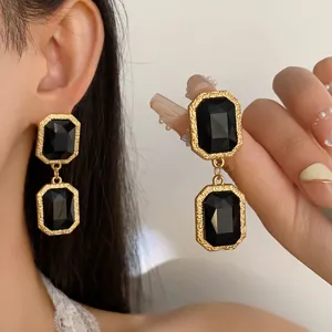Close-up detail shot of retro baroque black crystal drop earrings with ornate gold frames.