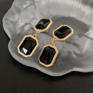 Close-up detail of vintage style gold-rimmed black crystal drop earrings, elegant craftsmanship.