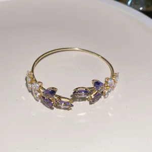 Exquisite gold-tone open cuff bracelet featuring purple and clear marquise crystal leaf details.
