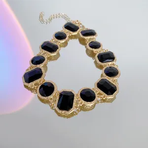 Close-up detail of vintage gold-toned statement necklace featuring black crystal rhinestones.