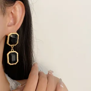 Close-up detail view of vintage retro black crystal earrings with textured gold frame design.