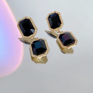 Detailed close-up of vintage black crystal drop earrings with textured gold-toned frames.