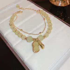 Elegant double layer green bead bracelet with cute peanut pendant, stylish gold chain jewelry.