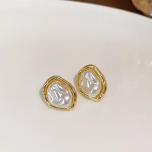 Detailed shot of irregular gold-rimmed pearl earrings, elegant and chic light luxury style jewelry.