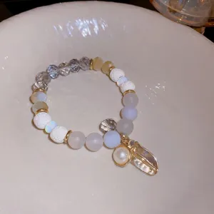 Close-up detail shot of a trendy multi-element beaded bracelet featuring crystals and charms.