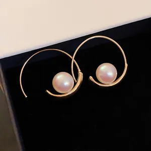 Detailed shot of elegant gold-toned hoop earrings featuring lustrous pearls in a black box.