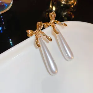 Detailed view of elegant French style gold bow white pearl long teardrop earrings fashion jewelry