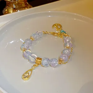 Crystal beaded bracelet detail shot showing transparent beads and gold teardrop charm.