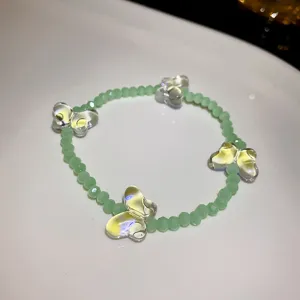Detailed view of the fresh green beaded bracelet featuring translucent crystal butterfly charms.