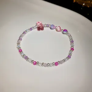 Close-up of sweet beaded bracelet with pink crystal beads and cute bear charm detail.