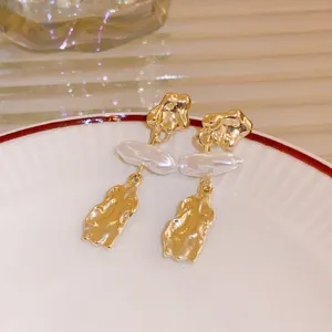Detailed shot of French light luxury irregular gold metal and baroque pearl drop earrings, elegant.