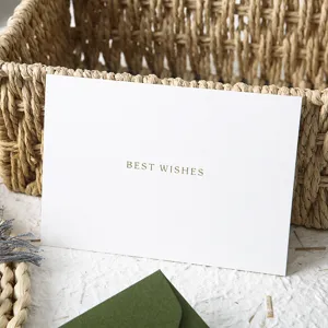Close-up of elegant white greeting card with best wishes text and green envelope.
