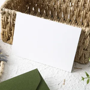 Detail shot of blank greeting card with avocado green envelope in rustic style basket display.