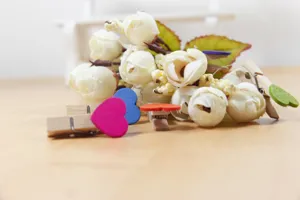 Detail view of colorful wooden heart clips set with artificial white roses decoration.