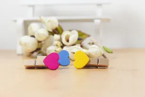 Close-up of colorful wooden heart clips on wooden table, ideal for photo hanging and decor.