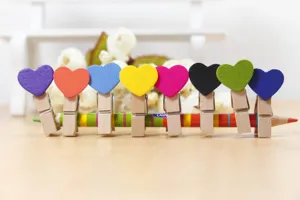 Wooden heart clips detail shot, colorful mini clothespins on a pencil, cute decor accessory.