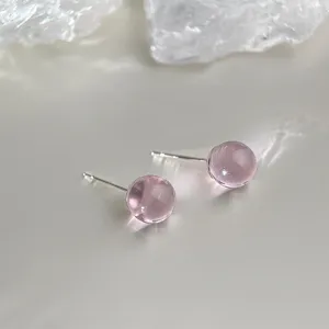 Detailed close-up view of elegant pink crystal ball stud earrings featuring translucent glass.