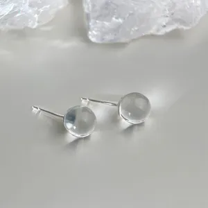 Detailed close-up of minimalist transparent crystal ball stud earrings, elegant and clear glass design.
