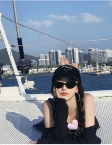 Close-up detail of stylish black oval sunglasses in a sunny yacht lifestyle scene setup.