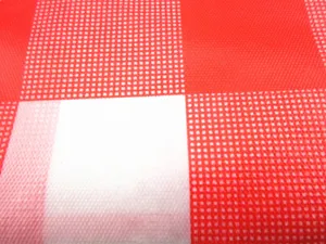 Vue rapprochée détaillée de la texture du matériel de nappe en plastique à carreaux rouges.