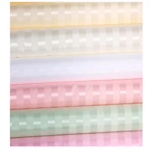 Detailed view of thick striped polyester fabric rolls in various soft pastel colors for decor.