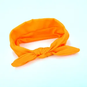 Close-up detail of the vibrant orange fabric knot headband, soft texture and cute bow design.
