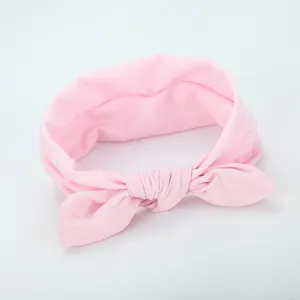 Close-up of soft pink fabric bow headband, delicate knot design, comfortable elastic hair accessory.