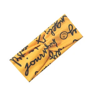 Detail des gelben Yoga-Stinbandes mit verdrehtem Knoten und schwarzem Aufdruck und Smiley.