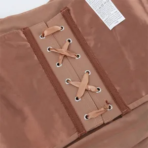 Close-up detail of women brown shapewear featuring cross lacing and metal eyelets mesh fabric.