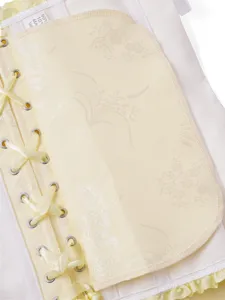 Detailansicht eines hellgelben Jacquard-Korsett-Tops mit Metallösen und Satinschnürung.