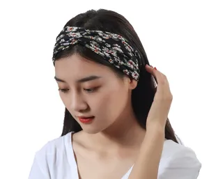 Close-up detail of the black floral printed twist headband worn by model, soft fabric accessory.